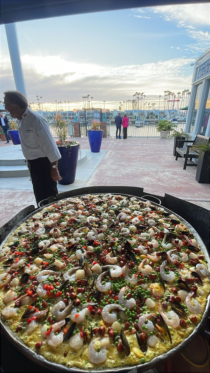 Paella gigante en un evento frente a la bahía al atardecer